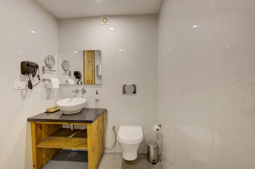 a white bathroom with a sink and a toilet at Cygnett Collection in Jim Corbett