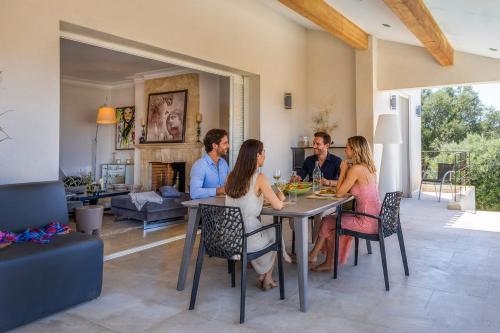 a group of people sitting at a table in a living room at Villa Bollaccia - piscine privée proche de la mer in Aregno