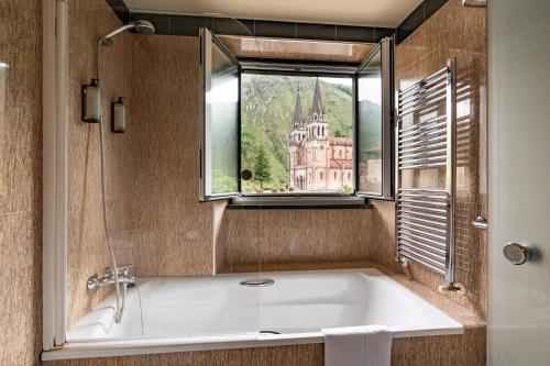 a bath tub in a bathroom with a window at Gran Hotel Pelayo in Covadonga