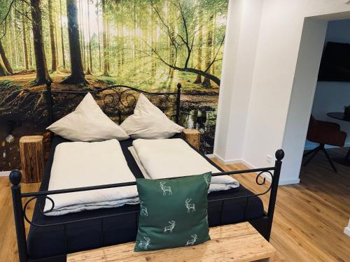 a bedroom with a bed with pillows and a forest mural at Urlaub Schwarzwaldliebe in Bad Teinach-Zavelstein