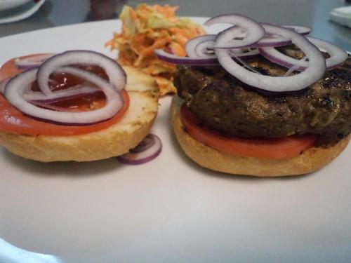 two hamburgers with onions and tomatoes on a white plate at Park House in Dej