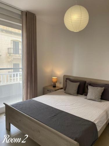 a bedroom with a large bed and a window at Link Point -Private room in shared Apartment in Misraħ Il-Barrieri