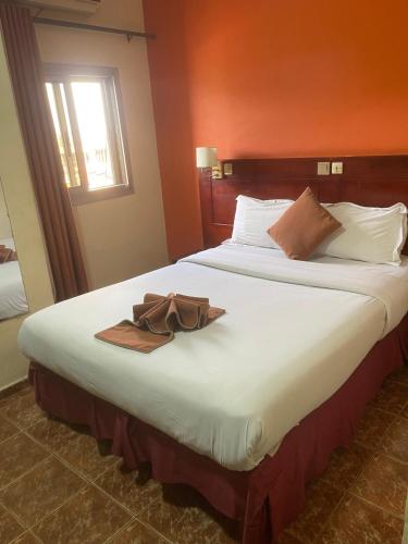 a hotel room with a large bed with a hat on it at Hotel Clamantis in Yaoundé