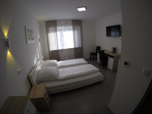a bedroom with a bed and a desk and a window at Pension Kochertal in Aalen