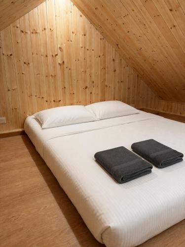 a white bed with two black towels on it at Miško Kortai in Menciškė