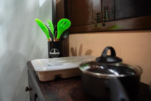 a kitchen counter with a pot and green utensils at Morada Coral Hostel em Maracaípe in Porto De Galinhas