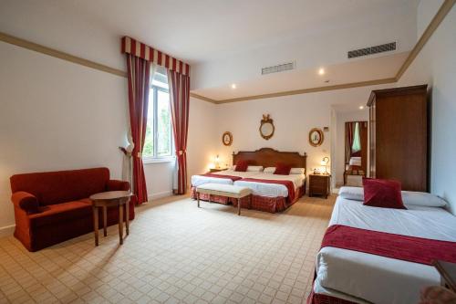 a hotel room with two beds and a chair at Gran Hotel Pelayo in Covadonga
