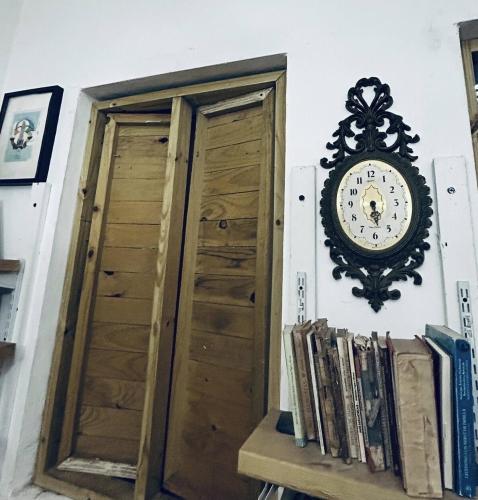 a clock hanging on a wall next to a shelf with books at Casa-Museo centro de Caguas in Caguas