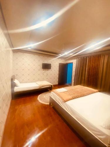 a small room with two beds and a ceiling at Hills n Huts in Hini