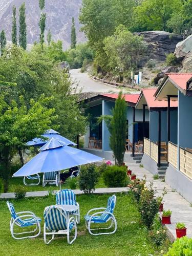 a patio with chairs and a blue umbrella at Hills n Huts in Hini