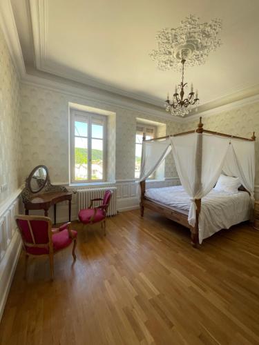 a bedroom with a canopy bed and a table and chairs at Le clos du Breuchin in Breuchotte