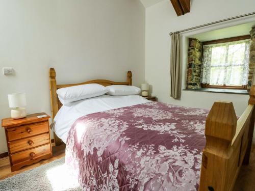 a bedroom with a bed with a purple blanket and a window at Bythyn Ddol Hafod in Capel Curig