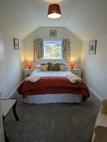 a bedroom with a large bed and a window at Foxbrae Cottage in Rockcliffe