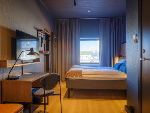 a bedroom with a bed and a desk and a window at Quality Hotel Grand Steinkjer in Steinkjer