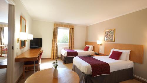 a hotel room with two beds and a desk at The Hickstead Hotel By Uno-FREE PARKING in Bolney