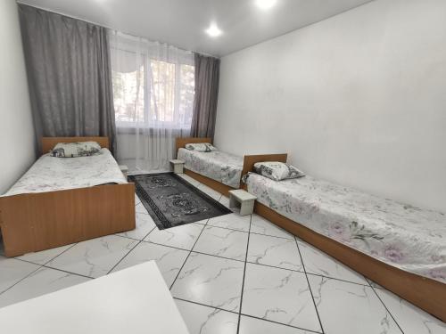 a room with three beds and a window at Rassvet in Lenīnogorsk
