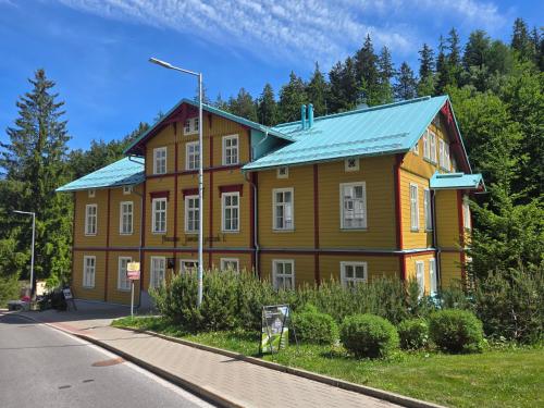 a large wooden building with a blue roof at Pension Janský Potok I. in Janske Lazne