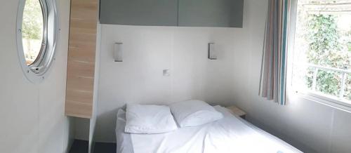 a bedroom with a bed with white sheets and a window at Camping 2 étoiles - Piscine - ccbfida in Vernet-les-Bains