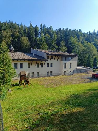 a large white building with a grass field in front of it at Pension Janský Potok II. in Janske Lazne