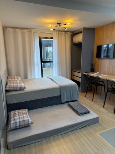a bedroom with two beds and a table and a desk at Studio aconchegante, moderno e completo in Ponta Grossa