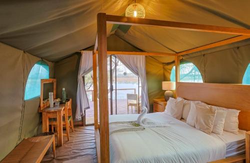 a bedroom with a canopy bed in a tent at Boteti Tented Safari Lodge in Maun