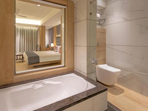 a bathroom with a bath tub and a bedroom at Hill Berry - A SoVo Hotel in Lonavala