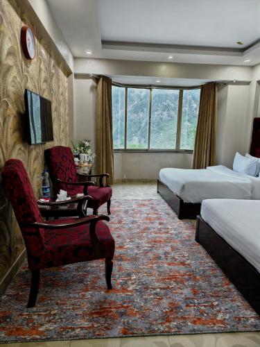 a hotel room with two beds and a table and chairs at Millennium Inn Hotel Naran in Naran