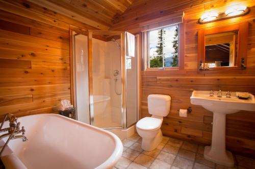a bathroom with a tub, toilet and sink at Paradise Lodge and Bungalows in Lake Louise