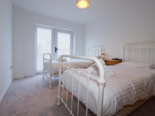 a white bedroom with two beds and a window at Eden's Bloomdale in St Austell