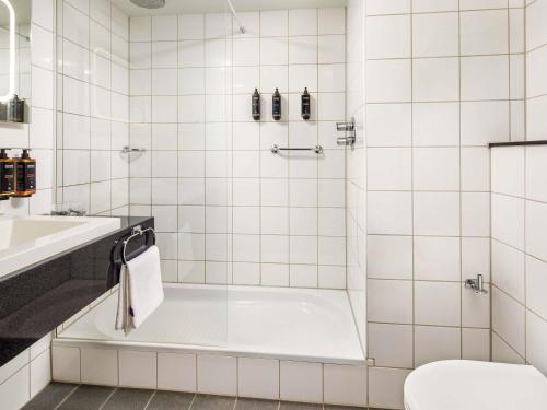 a white tiled bathroom with a tub and a sink at Mercure Nottingham Sherwood in Nottingham