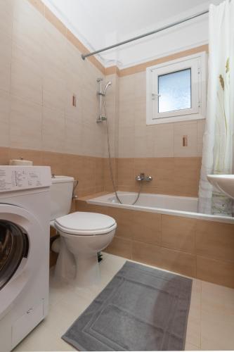 a bathroom with a toilet and a tub and a sink at The old inn in Laganas