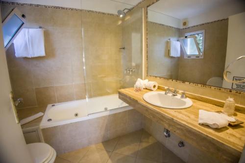 a bathroom with a sink and a tub and a toilet at Joan Miró Hotel in Punta del Este