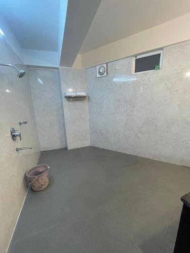 a bathroom with a shower with a window and a bucket at The Pham Inn in Bomdila