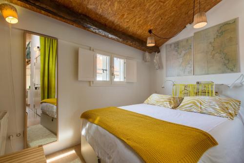 a bedroom with a bed with a yellow blanket at roomPEDRA apartamentos turísticos in Santiago de Compostela