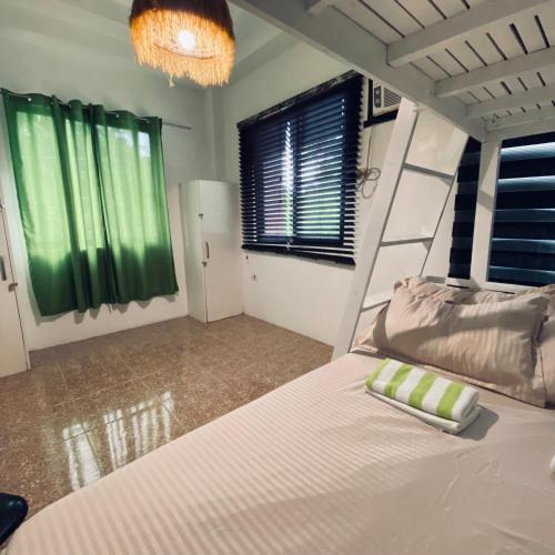 a bedroom with a large bed with green curtains at Duck & Drift - a Sleeper Hostel - Just 1,7km from Airport in Puerto Princesa City
