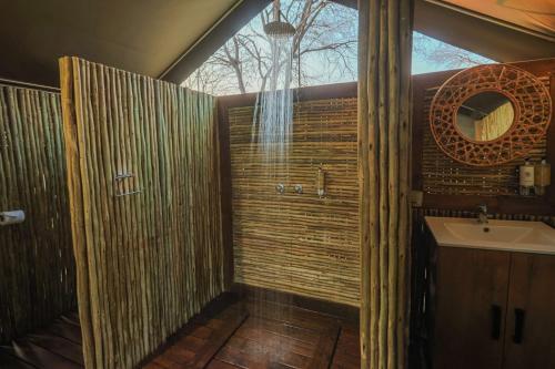 a bathroom with a shower and a sink and a mirror at Boteti Tented Safari Lodge in Maun