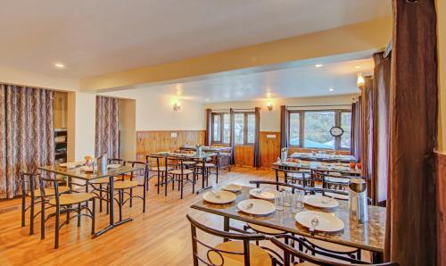 a restaurant with tables and chairs in a room at Hotel Monal Inn, Pangot Wildlife and Bird Sanctuary in Nainital