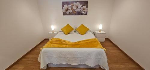 a bedroom with a bed with a yellow blanket on it at Casa dos Azevedos in Câmara de Lobos