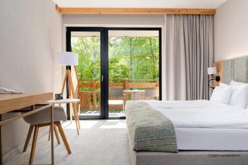 a bedroom with a bed and a desk and a balcony at Platinum Mountain Hotel&SPA in Szklarska Poręba