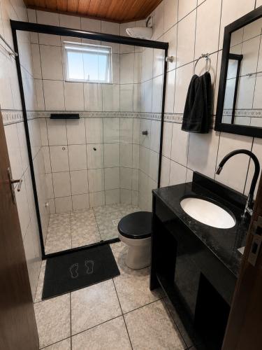 a bathroom with a shower and a toilet and a sink at Pousada das Águas in Piratuba