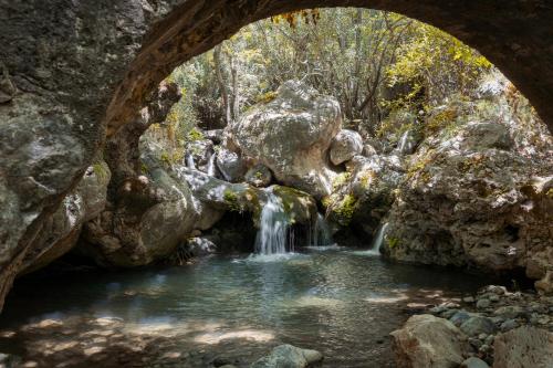 a stone cave with a waterfall in a pool of water at Manelis Mills Estate, Guest Houses & Restaurant in Plakias