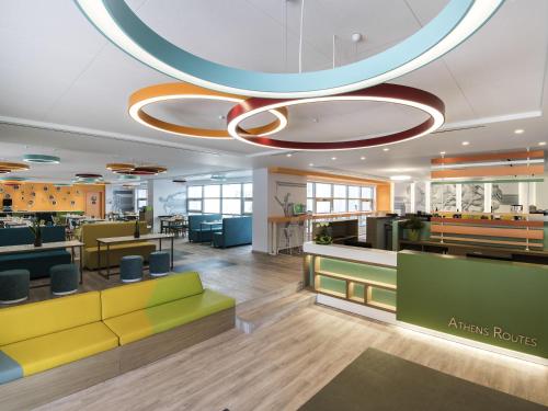 an office lobby with yellow and green furniture at ibis Styles Athens Routes in Athens