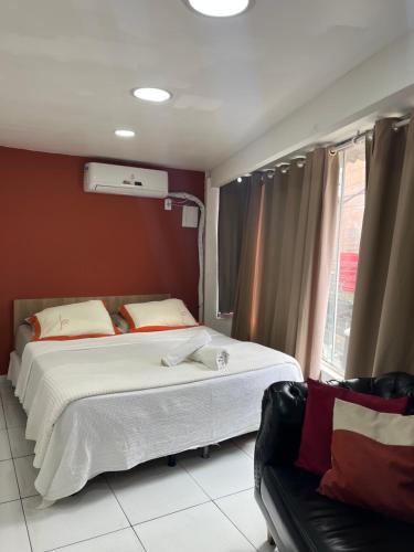 a bedroom with a large bed and a couch at Loft Aloha in Cabo Frio