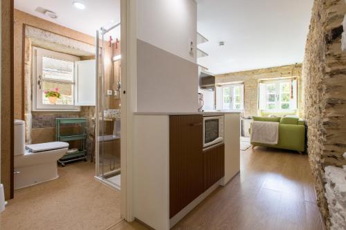 a kitchen with white cabinets and a living room at roomPEDRA apartamentos turísticos in Santiago de Compostela