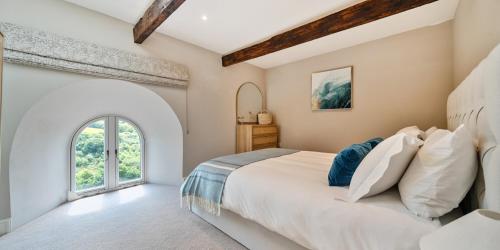 a bedroom with a large bed and a window at Brock's Beach House in Saint Gennys
