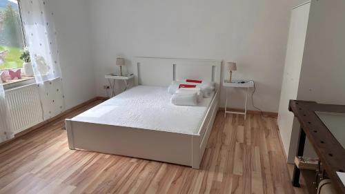 a white bedroom with a bed and a wooden floor at Ruhige Fewo Hinzweiler in Hinzweiler