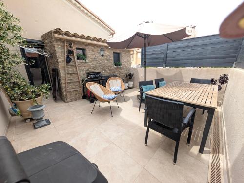 a patio with a table and chairs and an umbrella at Chambre ELENA in La Crau