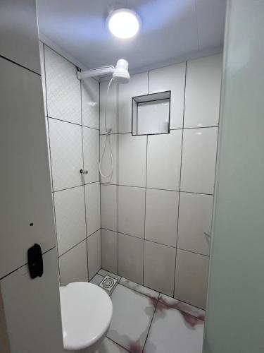 a white bathroom with a toilet and a light at Loft Aloha in Cabo Frio