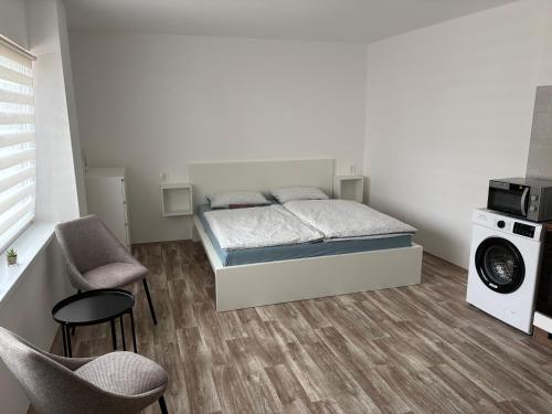 a bedroom with a bed and two chairs and a washing machine at Studio U Martina in Mariánské Lázně