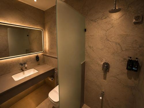 a bathroom with a sink and a toilet and a mirror at Avsar Resort in Verāval